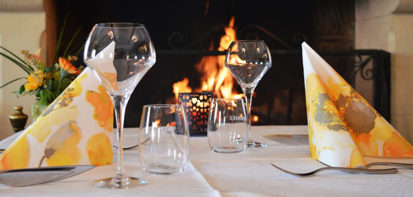 Verres de vin et assiette de fromages devant le feu de cheminée.