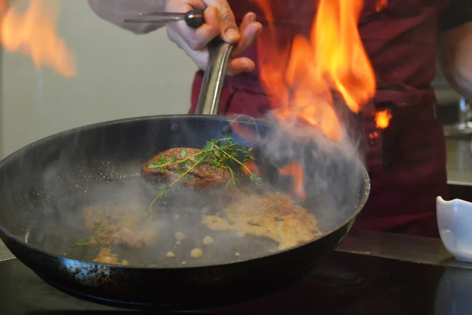 Le chef flambant une poêle au passe de la cuisine.