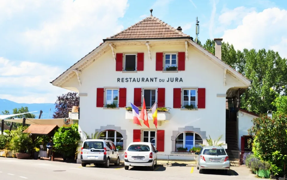 La façade du Restaurant du Jura et ses volets rouges, au centre de Chevroux.